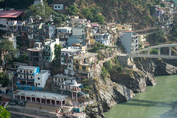 Obraz premium Sangam place of Alakhnanda and Bhagirathi River in Devprayag, Uttarakand. The surrounding building, man made structure, mountains make this place a must visit destination