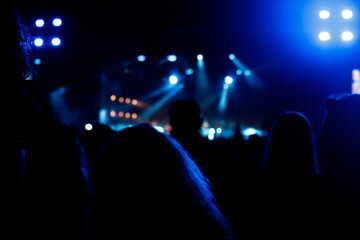 Silhouettes of spectators against a background of blue light at a concert