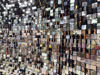 A wall of shiny silver tiles with a pattern of squares