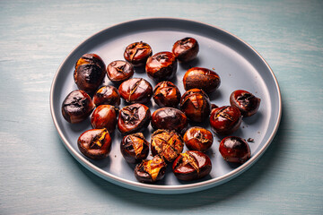 Roasted chestnuts on a blue plate. Close-up. View from above.