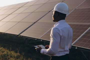 African American Engineer Inspecting Solar Panels at a Renewable Energy Farm