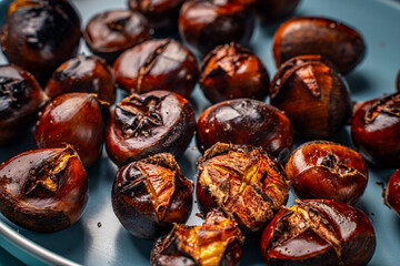 Roasted chestnuts on a blue plate. Close-up. View from above.