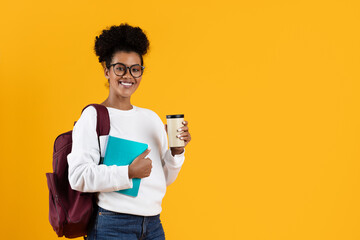 A friendly student stands confidently with a coffee cup in one hand and a notebook in the other. She wears a backpack, showcasing a relaxed yet prepared attitude for the day ahead, copy space