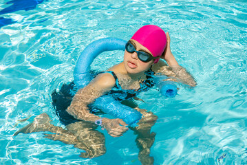 Girl with Down syndrome bathing in the pool on a summer day. inclusion, trisomy 21. wears diving...