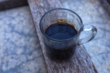 Black coffee in a clear glass is half finished inside, close up view.
