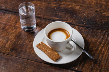 cafe macchiato coffee in white porcelain cup on wooden table