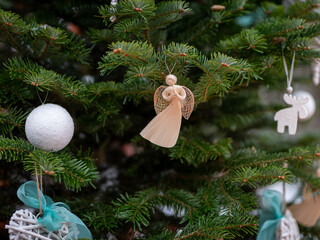 An angel and white and turquoise Christmas decorations on a Christmas tree.