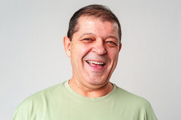 Smiling older man with a warm expression against a neutral background, showcasing happiness and joy