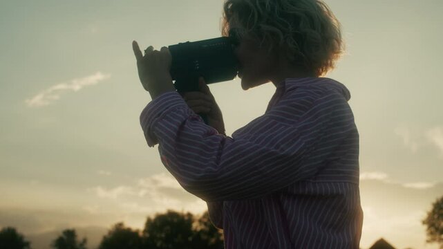 Camera girl filming in a flower garden with her super 8 vintage film camera