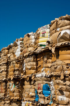 Compacted recycled paper bales stacked high in rows for recycling and processing.