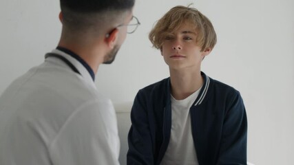 young kid doctor telling teenager boy good test result embracing and encouraging, giving high five each other. Friendly doctor talking to smiling happy teenager kid in examination room or at home