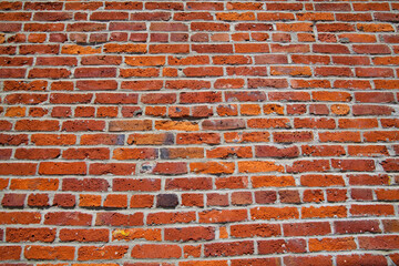 Brick wall detail, old weathered red bricks laid in an irregular pattern.