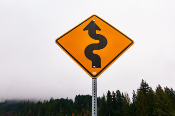 A yellow warning winding road sign, bends ahead. 