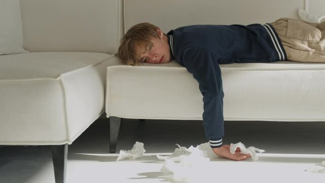 Sick tired exhausted weak little boy kid child teenager guy lying down on the bed feeling bad, having flu sneezing, running nose, cold 