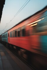 Fototapeta premium A colorful train blurs by, capturing the essence of travel and motion at dusk.