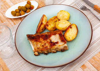 Delicious barbecued pork spare ribs served with baked potatoes on plate