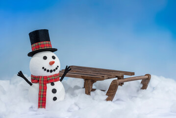 A happy snowman in a top hat and scarf, arms up and ready for winter fun! Posing with a sled on a...