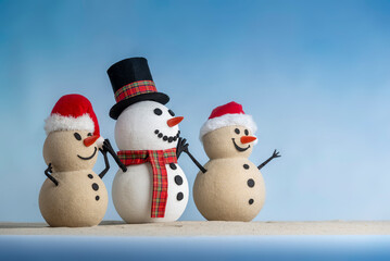 A joyful snowman and two sandy snowmen pose together for a Christmas and New Year celebration! With a snowy backdrop and blue sky, this mix of winter and beach vibes brings a fresh holiday twist.