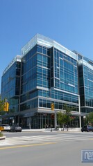 Modern glass office building with a clear blue sky and urban surroundings.