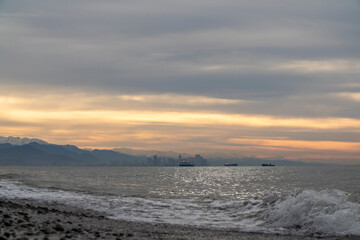 A sunset over calm water, with a vibrant city in the distance
