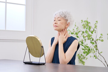 首のシワに悩む高齢者の女性