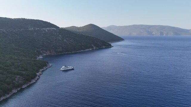 Beautiful view of a mountain as it is dropping to the side of the sea with a boat to the side on the coast.
