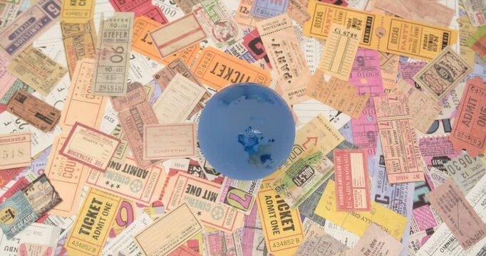 blue crystal earth globe on a bunch of vintage tickets from around the world, theater, movie, concerts, transport, boarding passes, hotel reception cards and other documents