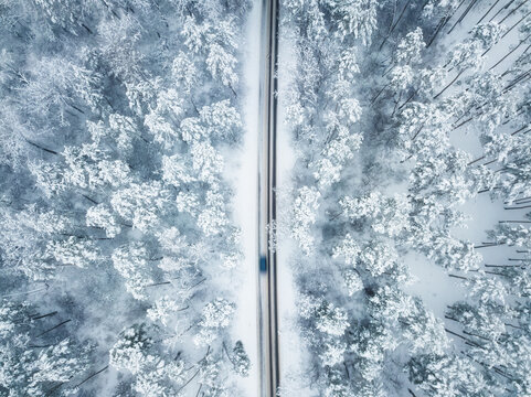 Aerial winter landscape. tranquil winter landscape captures a solitary vehicle traveling through a snow-covered forest in the heart of a serene wilderness