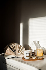 cozy home decor, cup of coffee, candle, books and a window on a warm warm autumn day.