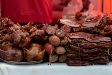 Selling smoked meat and salami at outdoor street market, closeup photo. Delicious smoked meat showcased on a red counter for sale