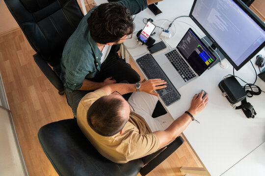 Top view of programmer diligently testing smartphone applications while sitting in their office.