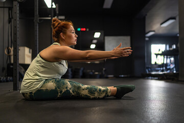 Determined woman practicing mobility exercise in modern gym space