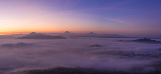 Fototapeta premium Hills in foggy evening. Radobyl hill in Czech Midland/ Ceske Stredohori, Czech republic