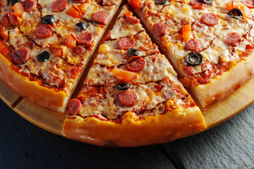Delight in a mouthwatering pizza adorned with pepperoni slices and black olives, fresh tomato pieces, and a rich swirl of sauce, perfect for any occasion.
