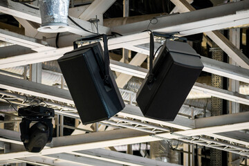 Powerful loudspeakers suspended from supporting structures under the ceiling of a large arena