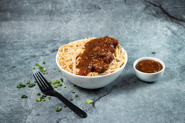 Kam heong chicken noodles with Spicy sauce, green onion and fork served in bowl isolated on grey background side view of asian food