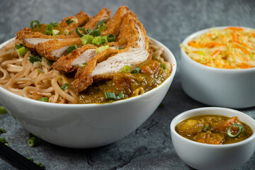 Katsu Chicken Noodles with potato curry, cabbage salad, green onion and fork served in bowl isolated on grey background closeup side view of Japanese food