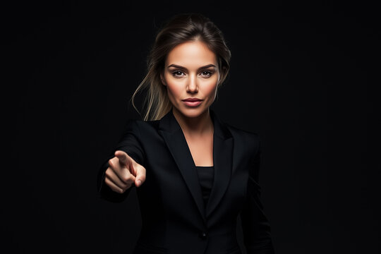 A determined woman in a black suit points directly at the viewer, exuding confidence and authority