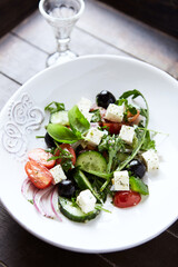 Healthy Salad with Feta Cheese, Black Olives, Cucumber and Cherry Tomatoes. Wooden background. Close up.