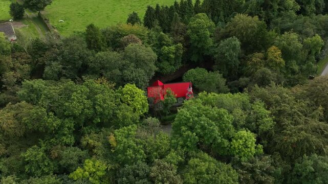 Saint Peter's Tin Church, Laragh, County Monaghan, Ireland, September 2022. Drone orbits counter clockwise around the charming Swiss Gothic style architecture surrounded by dense forest.