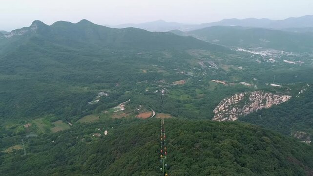 Aerial drone view of Dengfeng color Cableway near Shaolin temple in China. Cable cars run through forest near the Pagoda Forest and Shaolin Temple. Songshan Mountain in Dengfeng City, Henan Province.