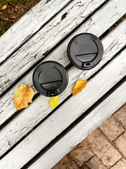 Two cups of coffee on a bench, autumn. Autumn landscape on a coffee bench.