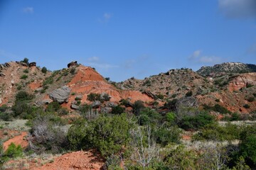 Scenic view of Palo Duro Canyon's red rock formations under a blue sky in Texas