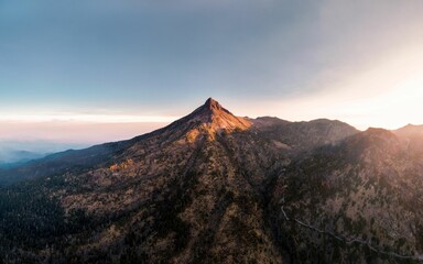 Aerial view of sunlit mountain peak at sunrise.