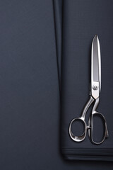 Top down view of grey cashmere, suiting fabric with sewing scissors, on the table of fashion design studio.
