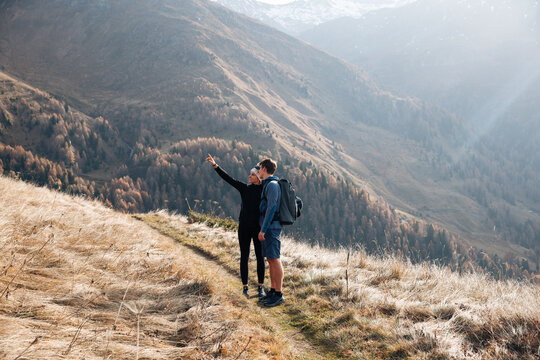 Hiking couple pointing toward distant mountains in Tyrol, Austria