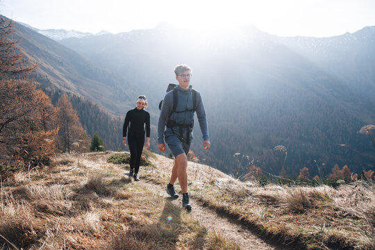 Two hikers walking along a sunny mountain trail in Tyrol, Austria