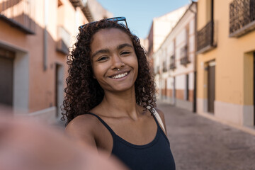 Young woman taking a selfie walking on a city street