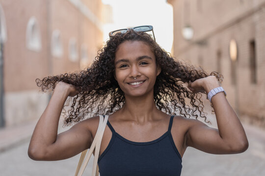 Happy young woman playing with her long curly hair