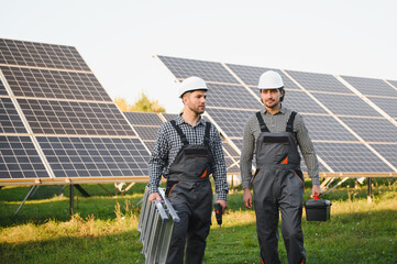 Two skilled workers or craftsmen wearing working gray uniforms, technicians are installing solar...